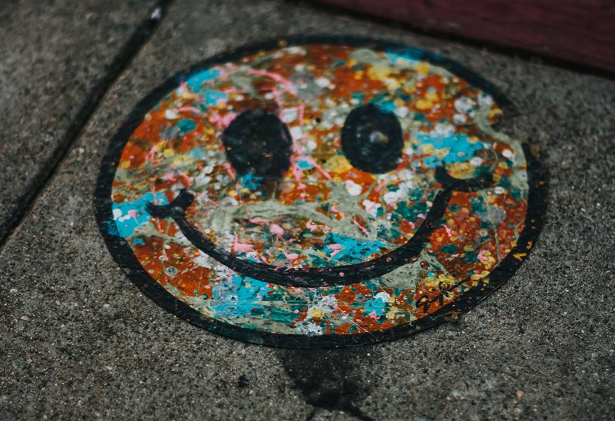Graffiti of colourful happy face on pavement - a photo by Devin Avery on Unsplash
