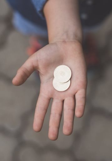 Hand offering two coins, cropped photo by Jordan Rowland on Unsplash